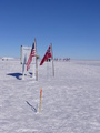 #6: Pole history: centennial (wooden stake), 1<sup>st</sup> January 2011 (between two flags), former stakes and Ceremonial Pole (surrounded by flags)