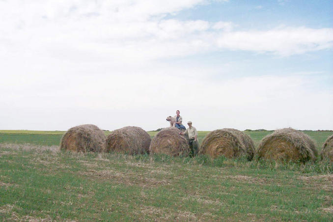 Max, Carolyn and Alan posing on huge bales of hay just south of the confluence.