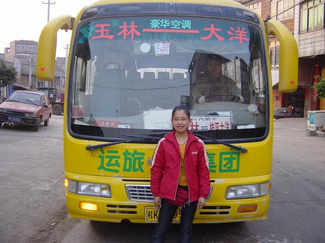 17-year-old ticket seller in front of bright yellow Yulin-to-Dayang bus.