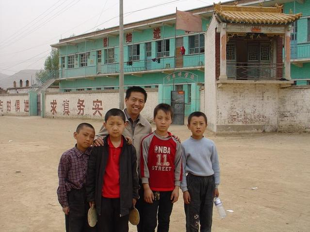 Xiao Baojin and children of Wan An Ping In the square(background is the School)/萧宝瑾和村里的孩子们在操场上合影，后面是小学