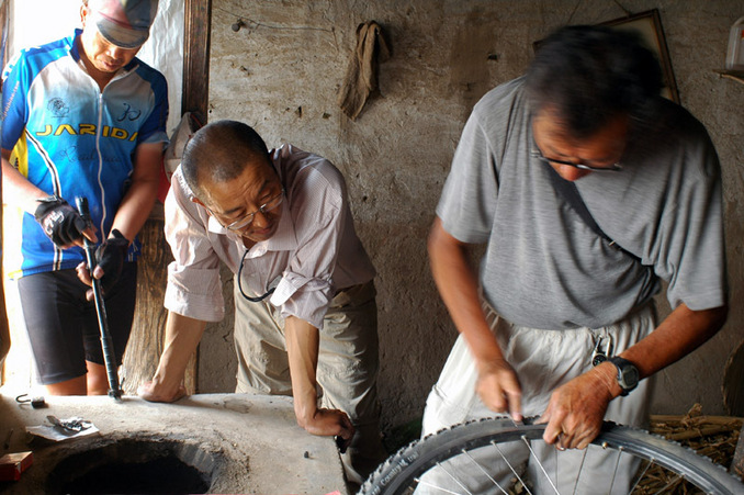 老李在田边的空房子里补胎 / Old Li repairing his bicycle tire in an empty shed by the field