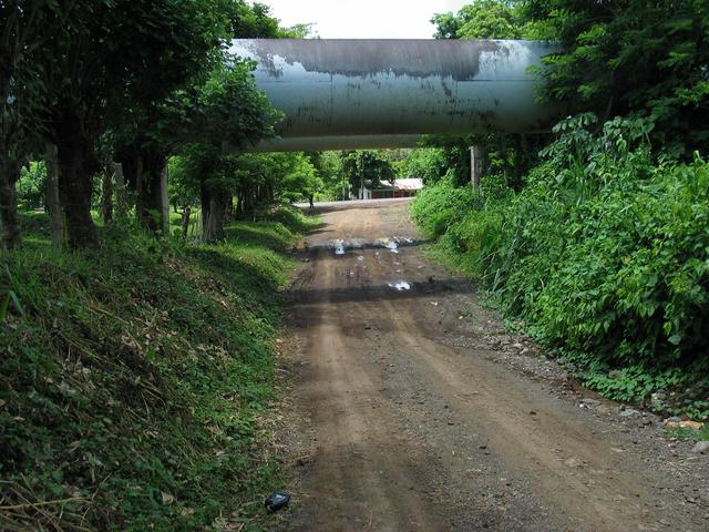 Road passing under pipeline. Store visible