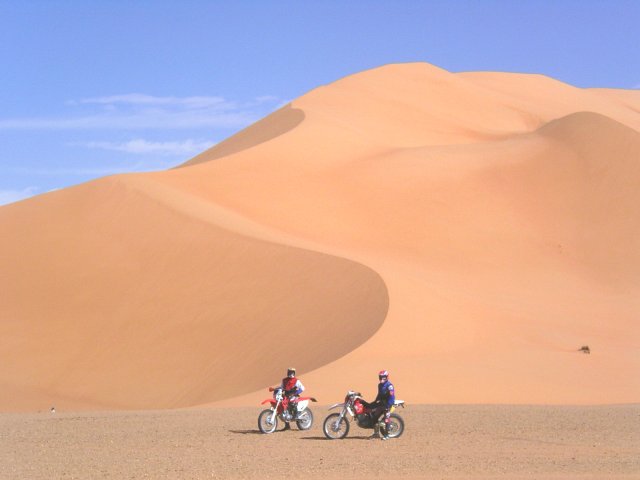 Two bikers against the sand dunes toward east