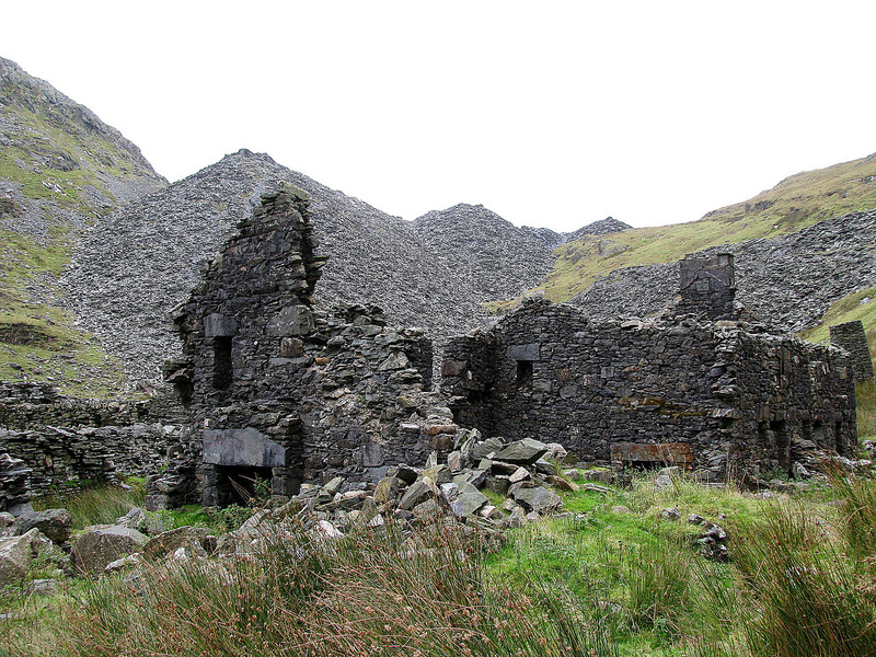 Quarrymen's row house ruins with some of the many slate waste heaps in the background.