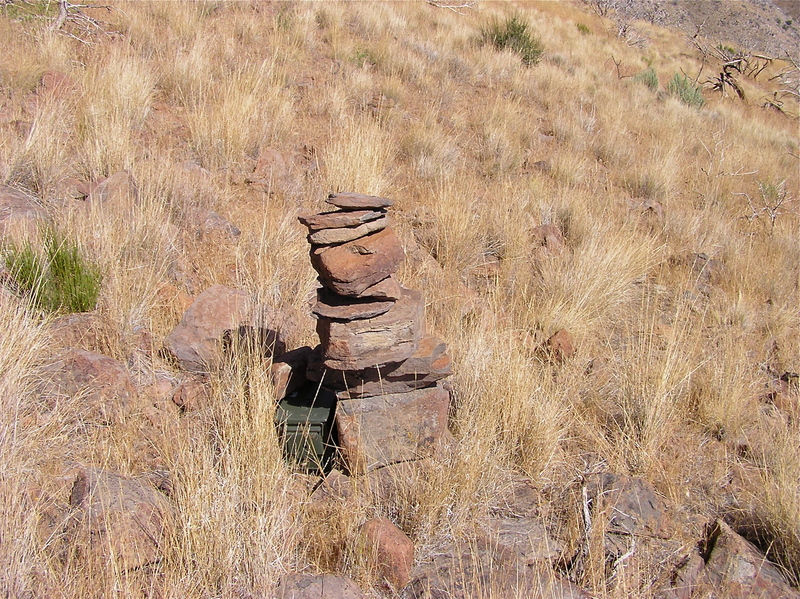 The confluence point lies near this rock cairn (and geocache), near the top of a rocky, grassy hillside