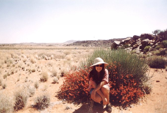 Anita in front of flowers (vehicle in background), looking west