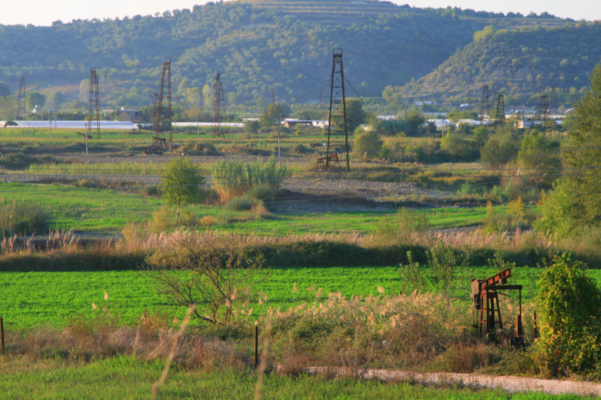 Oil rig towers sprout from fields at Kuçovë