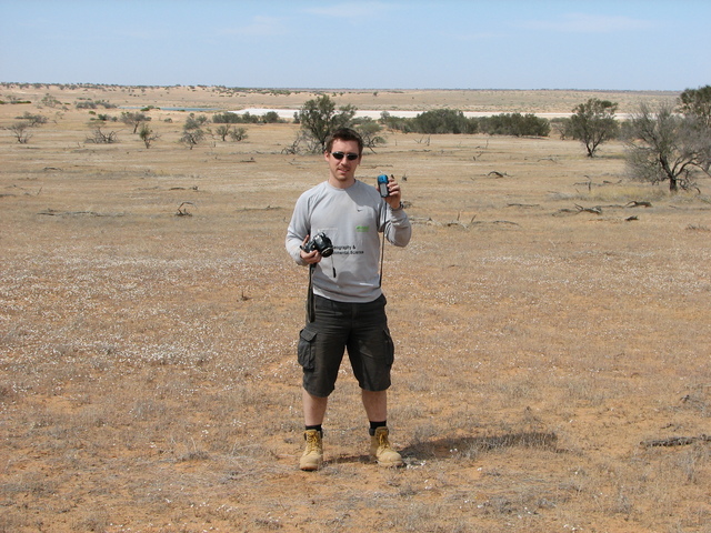 Picture of me standing at the Confluence Point with the dam in the left background