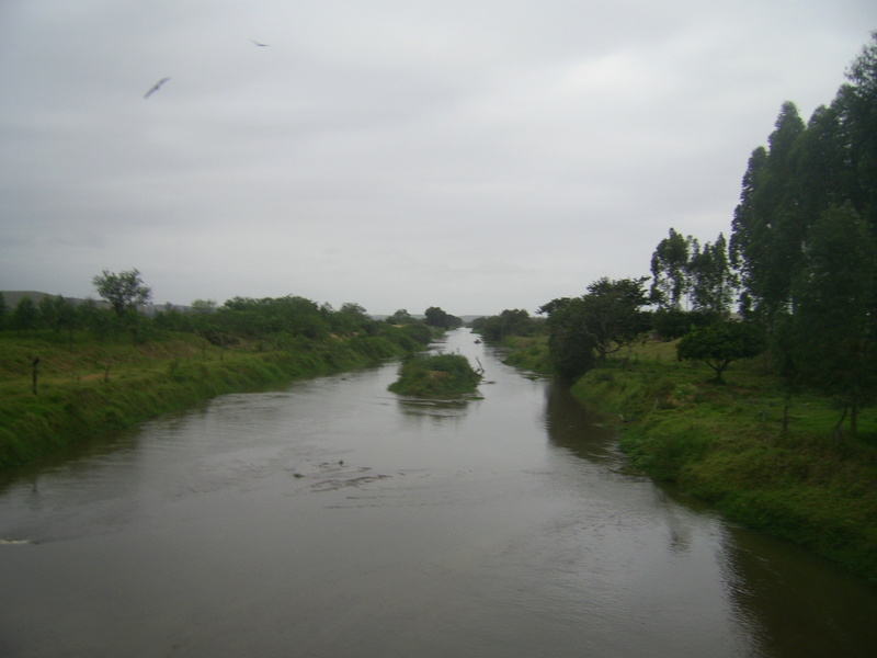 Rio que cruza a estrada de terra e segue margeando o pasto - river that crosses the dirt road and follows beside the pasture