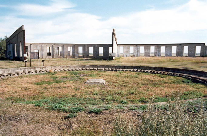 The remains of the turntable and roundhouse stand stark as ancient ruins against the prairie sky