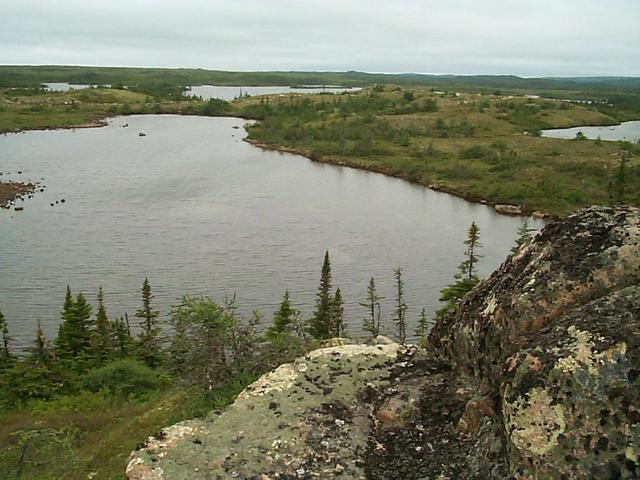 A view to the West shows the boulder-strewn glacial topography: numerous small lakes, scattered erratic boulders and low hills of glacial material. The stunted spruce and fir trees and the caribou moss has hardly had 10 000 years to get established!