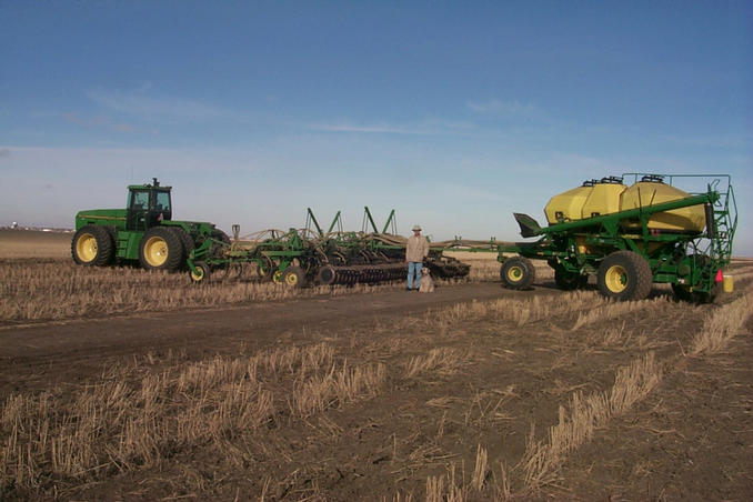 An "air seeder" being used to spread fertilizer on the field.  Avonlea can be seen in the distance on the left.