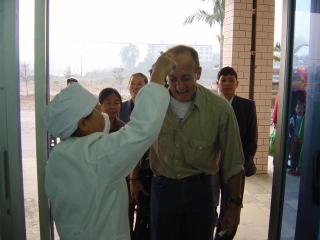 Richard feigning agony upon being zapped by the SARS temperature-taking gun as he enters the Qinzhou Railway Station