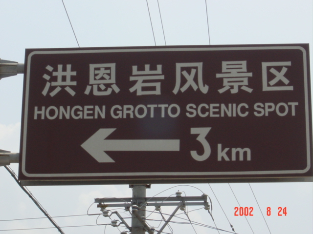 Large, bilingual sign, indicating the way to Hong'en Grotto Scenic Spot.