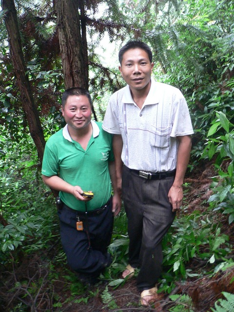 Targ's motorcyclist (holding the GPS) and another local at the confluence point, on a steep, densely forested hillside.