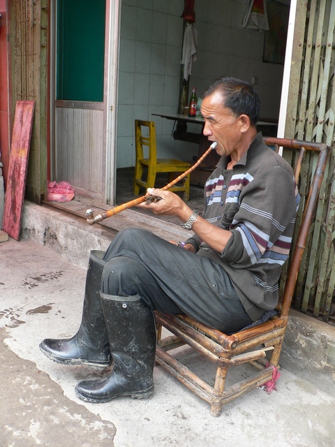Man smoking a pipe on the roadside in Dàtáng.