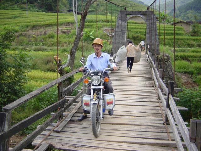 Village chief on motorbike crossing suspension bridge over Wenjiang River