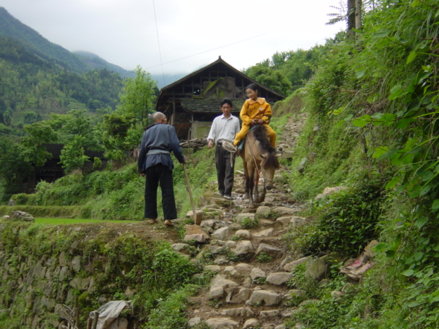 Young girl on horseback, making her way down a stone path into Tielu from somewhere in the surrounding countryside