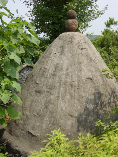 Two brown boulders seemingly precariously balanced atop one of the graves