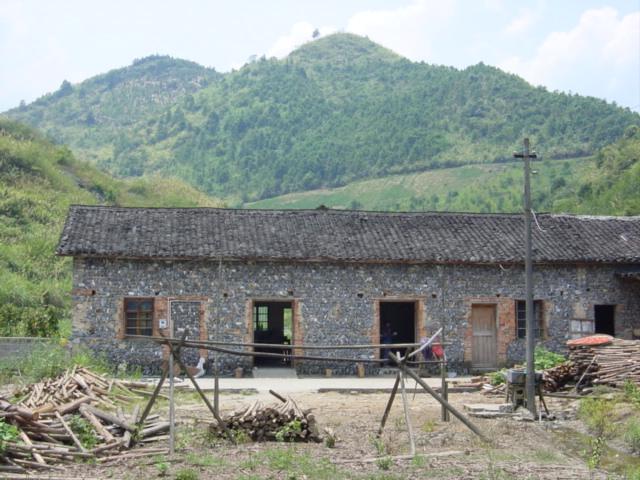 Confluence on road on hillside beyond farmhouse