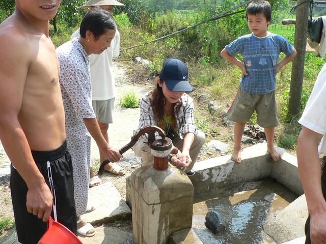 Ah Feng samples the refreshingly cool water Mr Fu's wife pumps from the well right next to the confluence point.