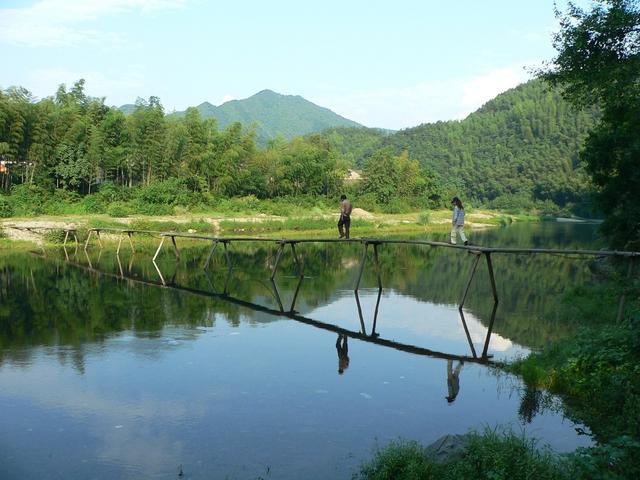 Mr Hu and Ah Feng crossing narrow wooden bridge.