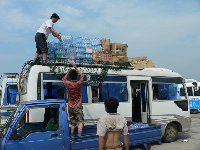 Loading roof of Liu'an-to-Wulong bus with bottled water prior to departure.