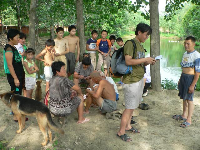 Locals enjoying card game by pond; Xiao Xu records name of village.