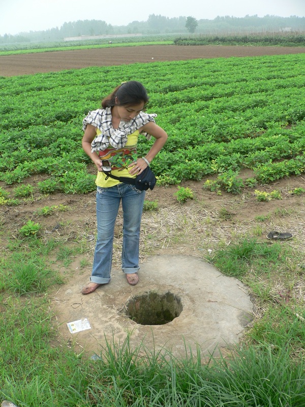 Ah Feng looking down a well in the middle of the fields