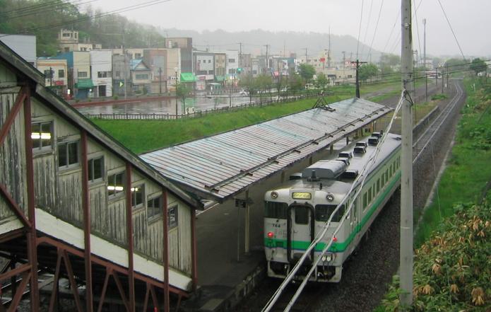 Shimizuzawa station with local train in foreground and town in background.