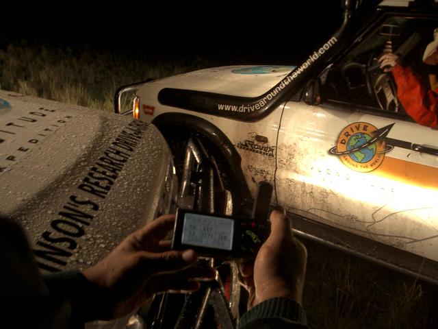 A teammember holds the GPS as the numbers tick down to zero.  The vehicles that got us there are Certified Land Rover Discoverys.