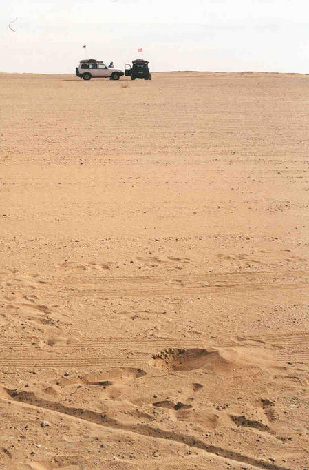 The photographs that were taken at the Confluence were unremarkable in their unremarkableness. This one shows the difference between the datums. Notice the AAA inscribed in the sand (look very carefully).