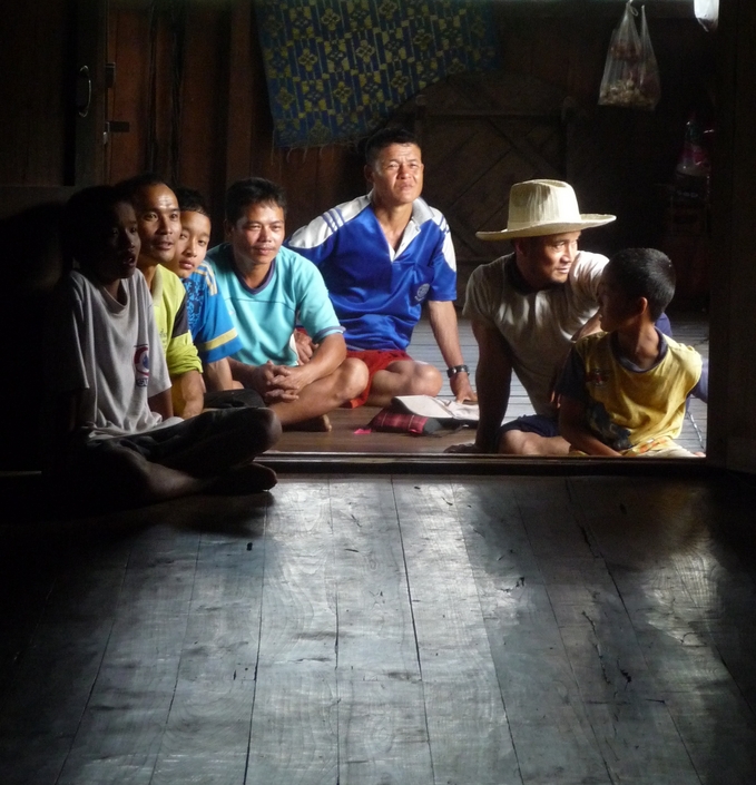 The Karen family inside their home in Umphang Ki.  Dit Ley is on the right in the cowboy hat with his boy in front of him.