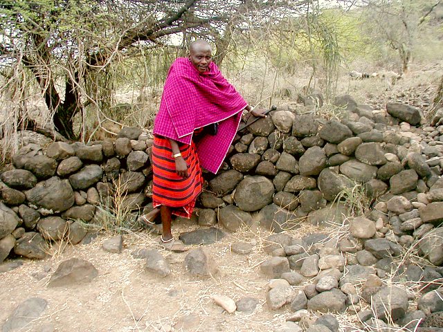 Chief standing in front of one of the strange walls that makes up the Engaruka Ruins archeological site