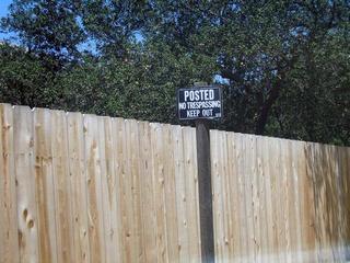 #1: Looking north towards the confluence with the view blocked by a fence and sign