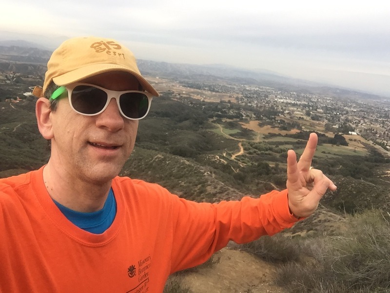 Joseph Kerski at the confluence point wearing Esri GIS cap.