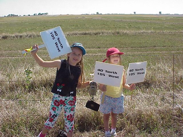 Young confluence hunters jubilantly display signs and GPS as site is found.