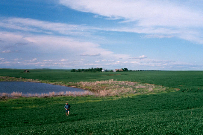 The confluence is behind John at edge of pond