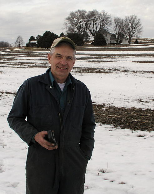 In an updated photo, semi-retired Farmer Dan stands at the most famous spot in his backyard.