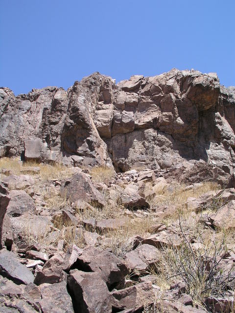 To the north a sharp rock face towers over a hundred feet above 36N 115W, which lies on the lower slopes at the east end of the McCullough Range.