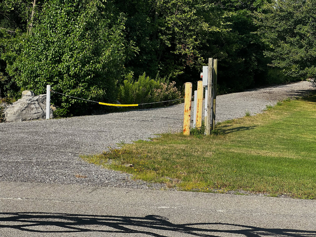 The entrance to the utility access path, off W. River Road, 0.94 miles West of the point