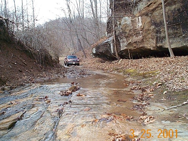 Access road in creek - Confluence is on hillside behind truck.