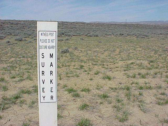 Sign at benchmark along road, 400 meters east-northeast of the confluence.