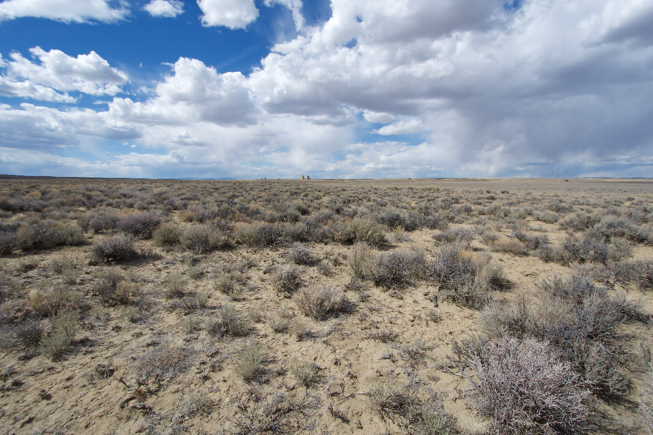 The confluence point lies in a sagebrush-covered plain.  (This is also a view to the North, showing oil fracking facilities nearby,)