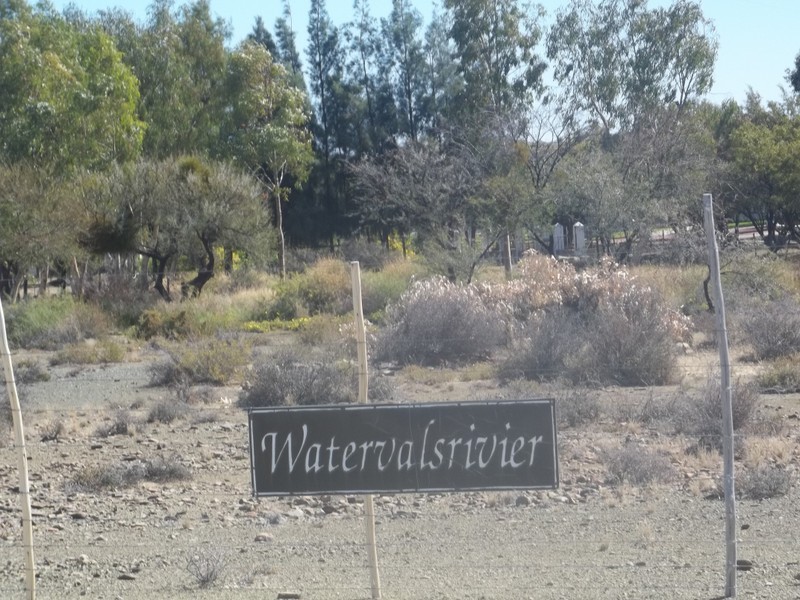 Farm buildings hidden by trees and name board